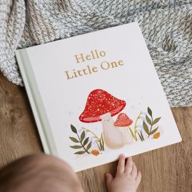 Personalised Fill-In-The-Love hardback baby book with woodland cover design on throw with baby's hand on book.
