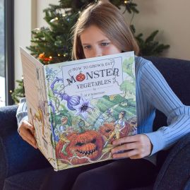 A young girl reading a book with a Christmas tree glowing in the background.