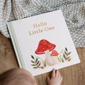 Personalised Fill-In-The-Love hardback baby book with woodland cover design on throw with baby's hand on book.